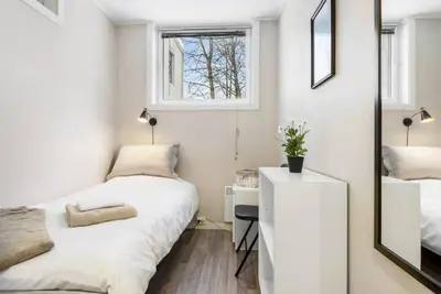 a small bedroom with two beds and a mirror at 1-roms leiligheter med felles bad, stue og kjøkken in Steinkjer