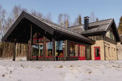 a large building with red doors in the snow at Solheimen konferansehotell AS in Hedalen