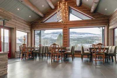 a dining room with tables and chairs and windows at Solheimen konferansehotell AS in Hedalen