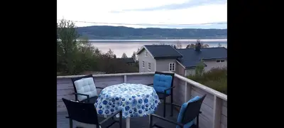 a table and chairs on a balcony with a view of the water at Holiday house by Lake Mjosa, 4 beds in Eidsvoll