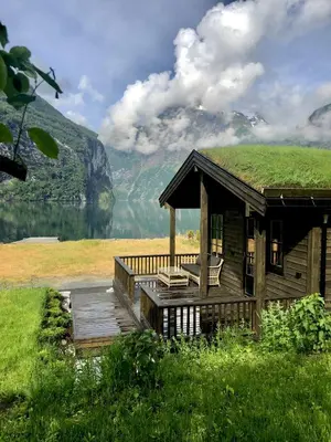 a cabin with a grass roof with a view of a lake at Cabin by the fjord in Geiranger
