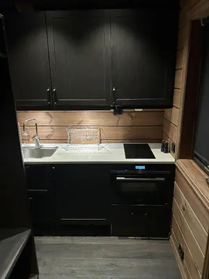 a kitchen with black cabinets and a sink at Cabin by the fjord in Geiranger