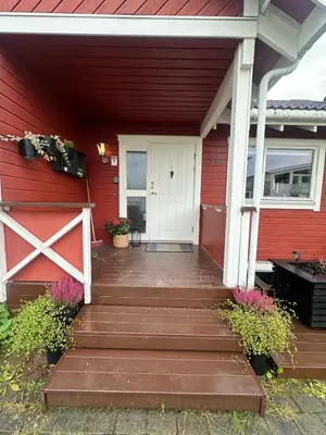 a red house with a wooden porch with a white door at House near Granåsen Ski Arena in Trondheim