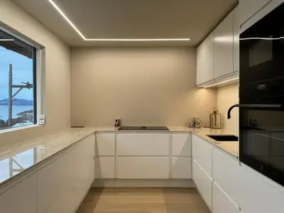 a kitchen with white cabinets and a large window at Modern Home with a View, Easy access to World Ski Championships in Malvik