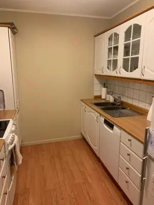 a kitchen with white cabinets and a wooden floor at 2 bedrooms apartment in Trondheim