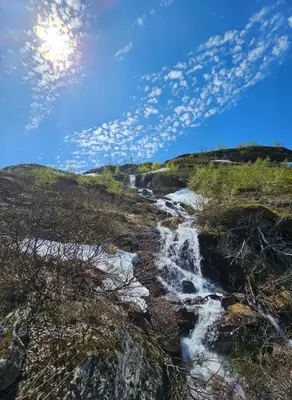 a waterfall on the side of a hill with a cloudy sky at Mountain view 1 in Håra
