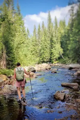 a person walking across a stream with a stick at Veslekoia - Grandmas Cabin in Øksna