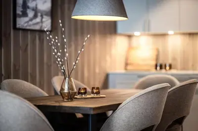 a wooden table with chairs and a vase of flowers at Cozy ski in & out apartment in Kyrkjebøen