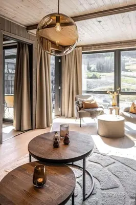 a living room with two tables and a living room withwindows at Cozy ski in & out apartment in Kyrkjebøen