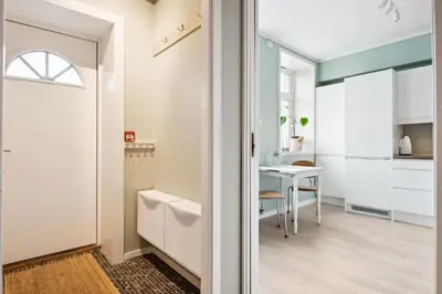 a kitchen and dining room with a table and a door at Sjarmerende leilighet med utsikt, spa-bad og park in Bergen