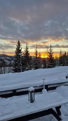 a bench covered in snow with the sunset in the background at Trysil Campingvogn Ski in-out in Trysil