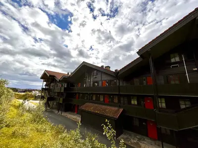 an apartment building with red doors and a cloudy sky at Cozy Top-Floor Apartment With Fireplace And Sauna in Beitostøl