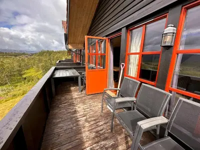 a deck with chairs and an orange door on a train at Cozy Top-Floor Apartment With Fireplace And Sauna in Beitostøl