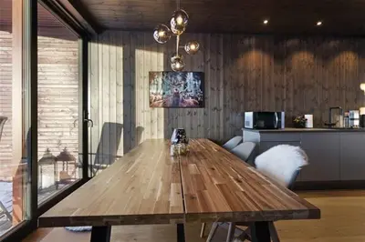 a wooden table in a living room with a kitchen at Ski in-out - 3BR, 2 Bath Chalet apartment - Favn Hafjell in Hafjell