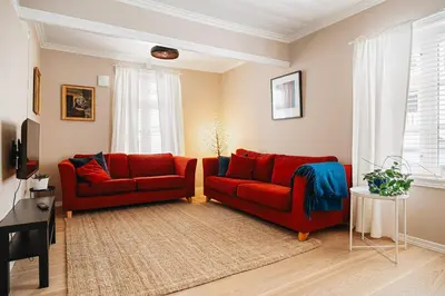 a living room with two red couches and a rug at DINBNB Homes l Charming 2-Bedroom Home by the Sea Cozy in Bergen