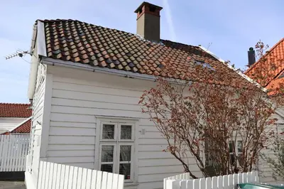 a white house with a white fence in front of it at DINBNB Homes l Charming 2-Bedroom Home by the Sea Cozy in Bergen