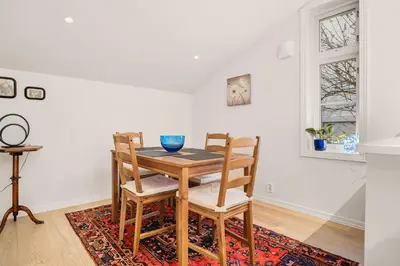 a dining room with a table and chairs on a rug at DINBNB Homes l Charming 2-Bedroom Home by the Sea Cozy in Bergen