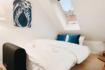 a bedroom with a bed with white sheets and blue pillows at 200m to Torgalmenningen & 20 sqm terrace in Bergen