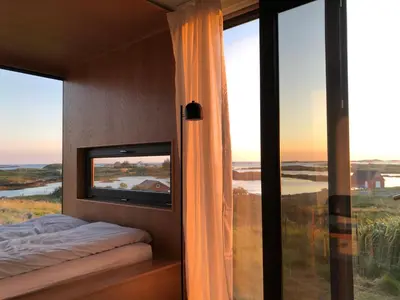 a bedroom with a tv and a large window at Smøla Sleeping Experience Re-Treats in Steinsøynes