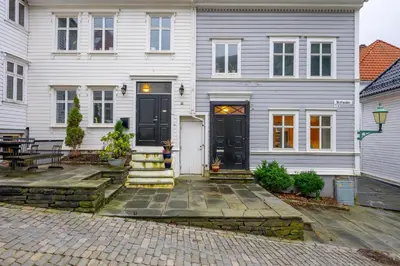 a white house with a black door and stairs at Modern Apartment in 1840-Building at Nordnes in Bergen