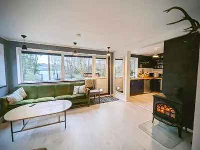 a living room with a green couch and a fireplace at Fjord View Cabin Near Bergen & Nature in Grottveit