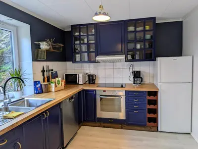 a kitchen with blue cabinets and a white refrigerator at Fjord View Cabin Near Bergen & Nature in Grottveit