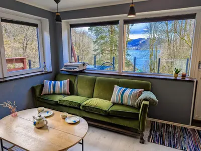 a living room with a green couch and a table at Fjord View Cabin Near Bergen & Nature in Grottveit