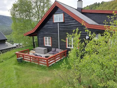 a black house with a deck in front of it at Charming Cabin Near Hallingskarvet Ski Center, Cozy and Inviting! in Skoro