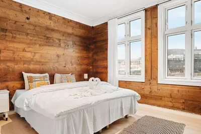 a bedroom with a bed with wooden walls and windows at Dinbnb Home - History meets Modern I 3-Story Bergen House in Bergen