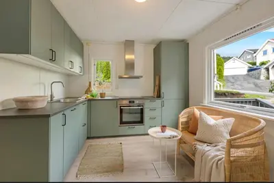 a kitchen with green cabinets and a couch and a window at Cozy Apartment in Lillehammer in Lillehammer