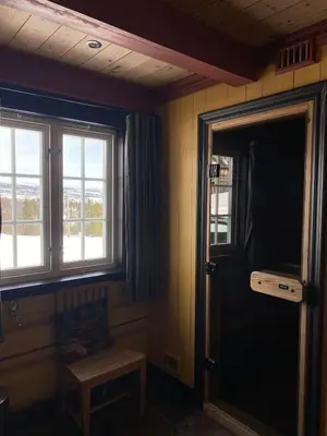 a room with a door and a chair and windows at Kvenahytta in Markegardlian