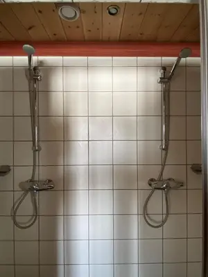a bathroom with two shower heads on a tiled wall at Kvenahytta in Markegardlian