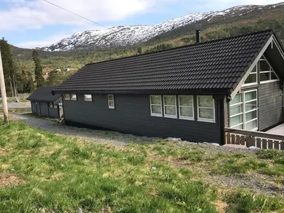 a black house with mountains in the background at Amazing home in the heart of Nordfjordeid in Nordfjordeid