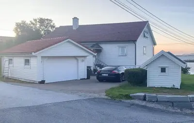 a white house with a car parked in the driveway at 4 Bedroom Gorgeous Home In Atløy in Herland