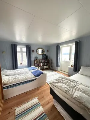 two beds sitting in a room with wooden floors at Kystperle med utsikt, lei en båt in Namsos