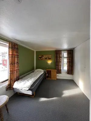 a bedroom with a bed and two windows at Kystperle med utsikt, lei en båt in Namsos