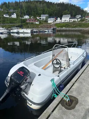 a white boat parked at a dock in the water at Kystperle med utsikt, lei en båt in Namsos