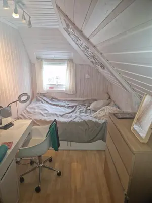 a bedroom with a bed and a desk and a chair at Sentrumsnær stor leilighet in Trondheim
