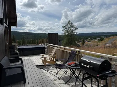 a patio with a grill and chairs on a deck at Skogbrynet hytte in Svingvoll