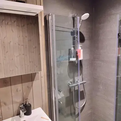 a shower in a bathroom with a glass shower backdoor at Skogbrynet hytte in Svingvoll