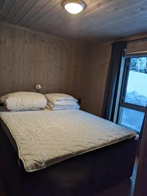 a large bed in a room with a window at Skogbrynet hytte in Svingvoll