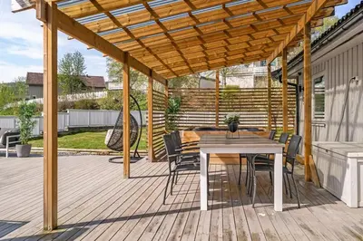 a wooden deck with a table and chairs under a wooden pergola at World Cup Trondheim 2025 in Trondheim