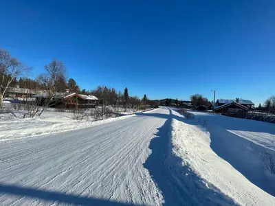 a road covered in snow with a long shadow at Charming Mountain Retreat Near Ski Trails And Beitostølen Center in Beitostøl