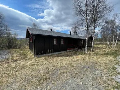 a small black house in the middle of a field at Charming Mountain Retreat Near Ski Trails And Beitostølen Center in Beitostøl