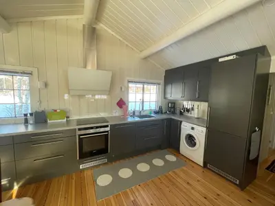 a kitchen with black cabinets and a washer and dryer at Charming Mountain Retreat Near Ski Trails And Beitostølen Center in Beitostøl