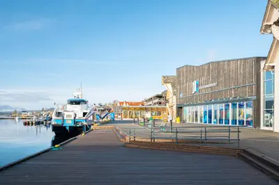 a boat is docked at a dock next to a building at Gildeskaal - A Fairytale Stay in Rosendal in Rosendal