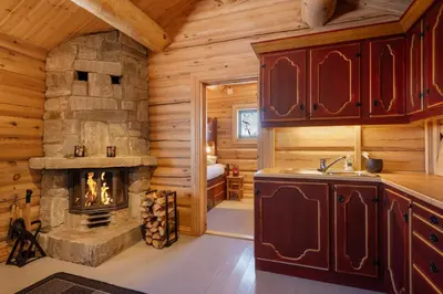 a kitchen with a fireplace in a log cabin at Koselig hytte Gålå Vakre Lauvåsen in Sør-Fron