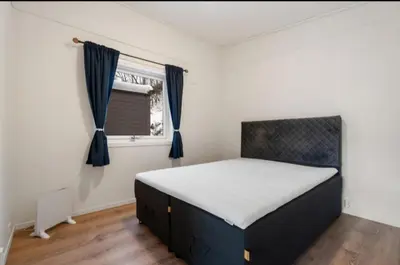 a bedroom with a bed with blue curtains and a window at Guesthouse-Ølen, 2 bedroom in Dørheim