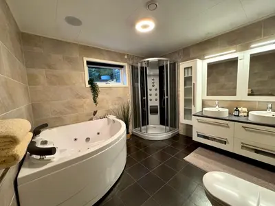 a bathroom with a tub and two sinks and a toilet at Appartment with garden in Malvik