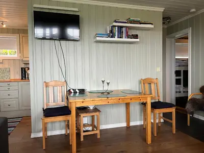 a dining room table with two chairs and a television on the wall at Skiidyll Med Utsikt Og Peis in Beitostøl